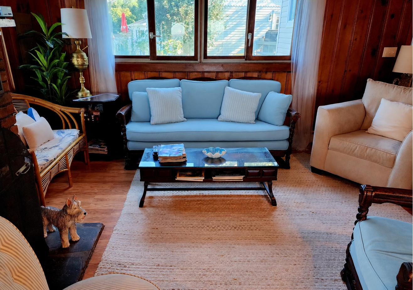 Cottage 1 living room with wood paneling, a light blue sofa, and the brick fireplace