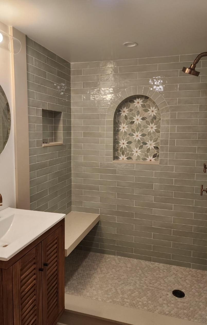 Bathroom at Cottage 1 with sage green subway tile and a floral mosaic niche
