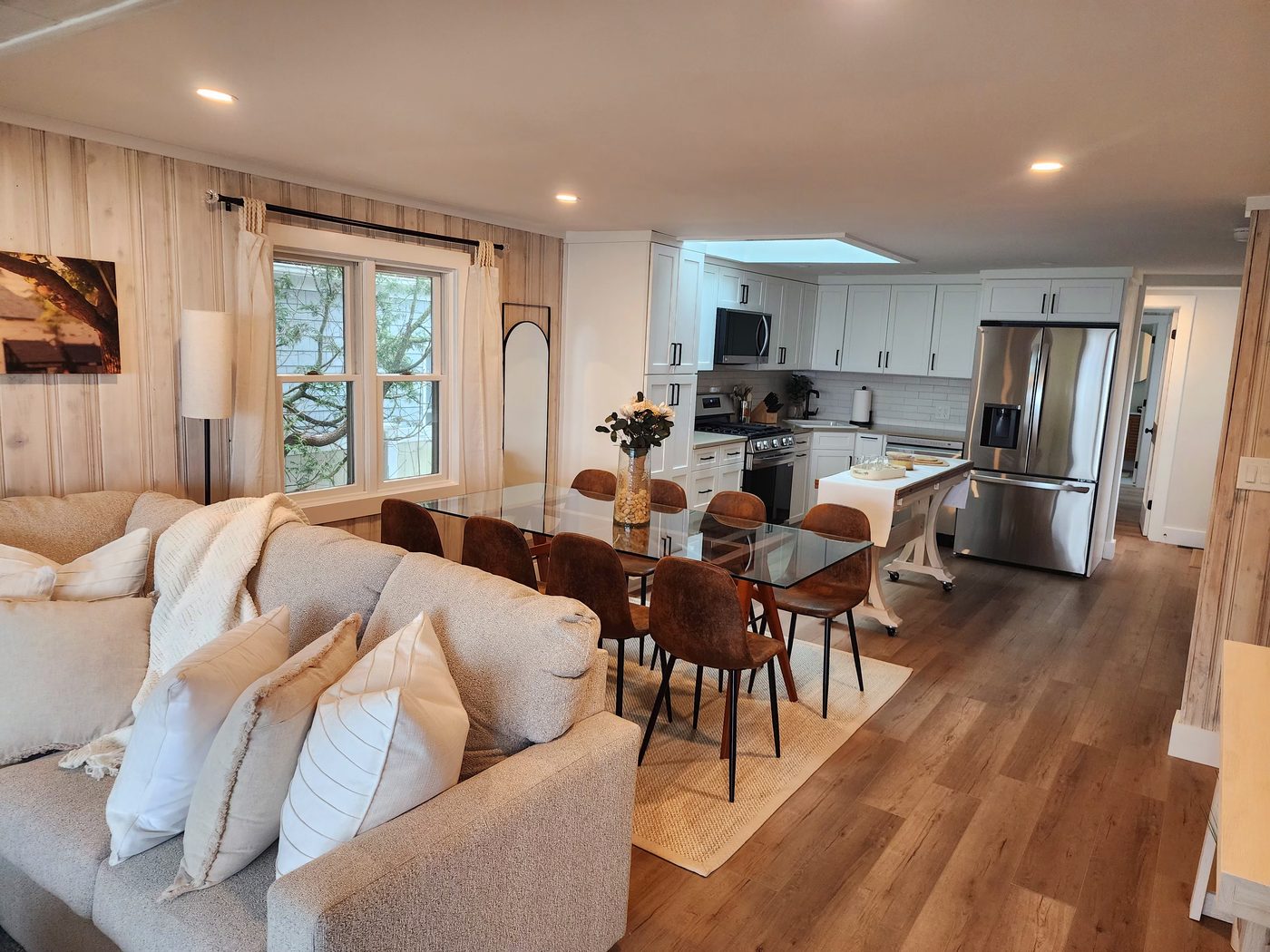 Open-concept kitchen, dining, and living space at Cottage 2 with a skylight and glass dining table