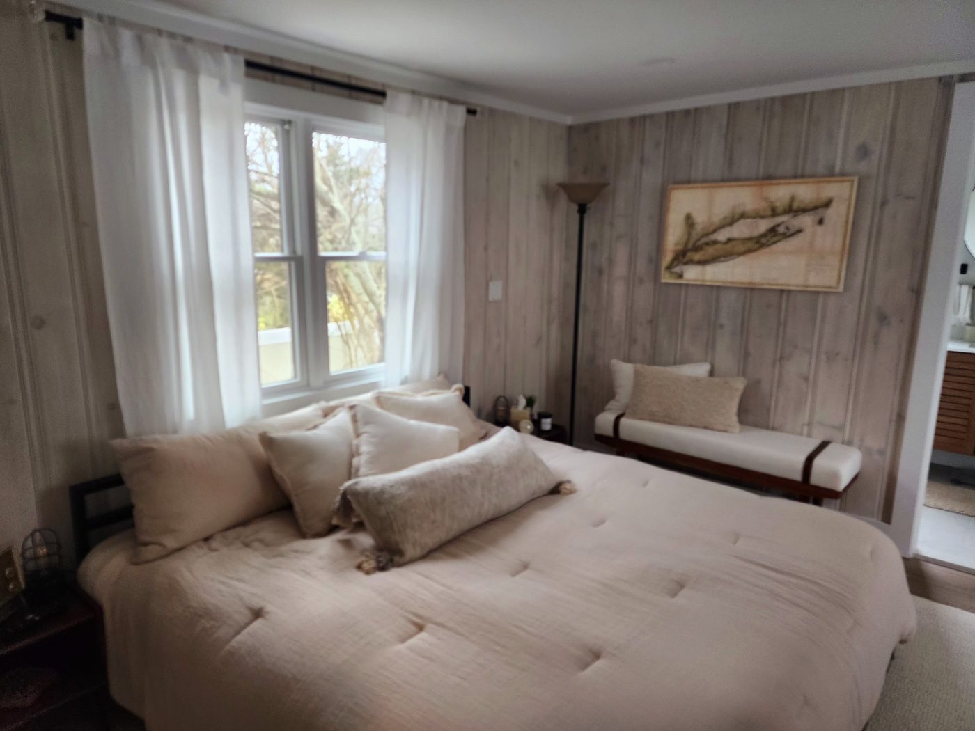 Primary bedroom at Cottage 2 with whitewashed wood walls and local map art