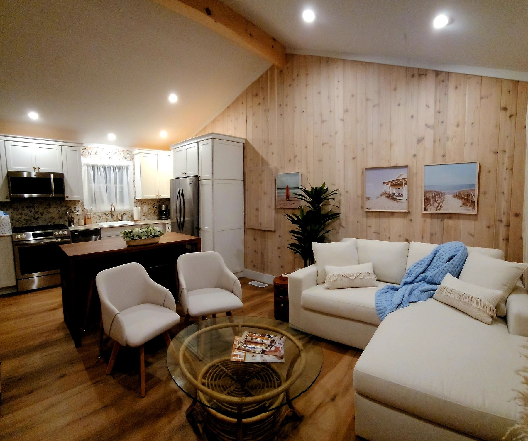 Vaulted, whitewashed living and kitchen area at Cottage 4, with a floral-tile backsplash and wood accent wall