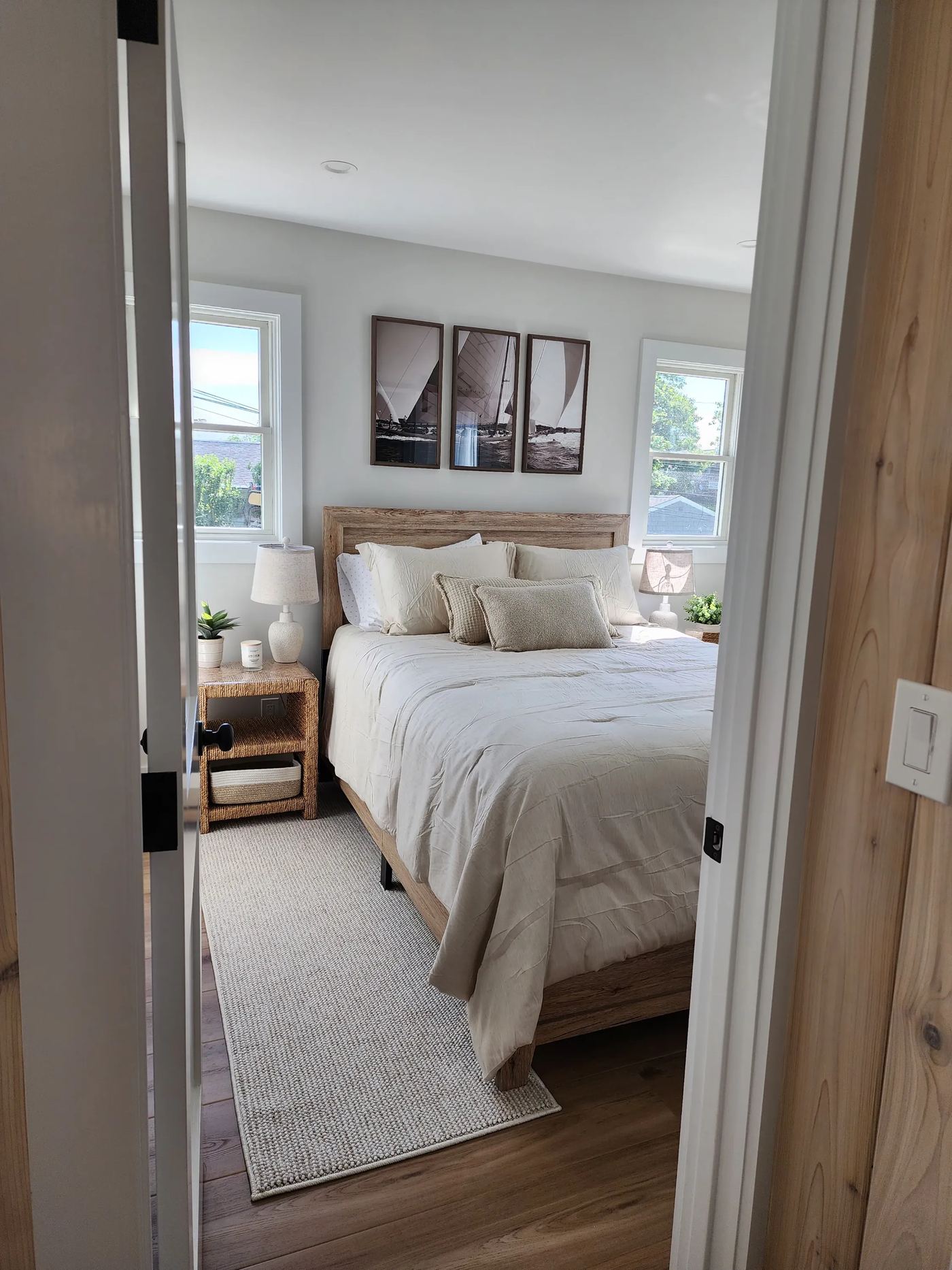 Cottage 4 primary bedroom with sailing photography above a wood bed frame