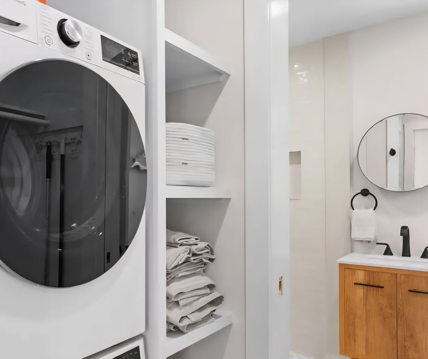 Stacked washer and dryer with open shelving, leading through to the Cottage 4 bathroom