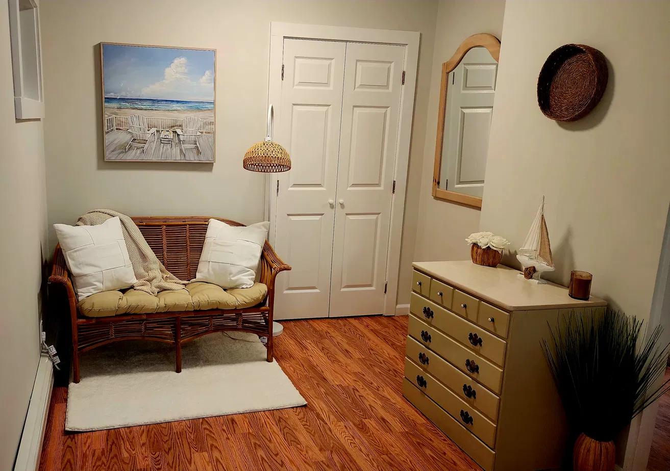 The primary bedroom's sitting area, with a rattan loveseat and beach artwork