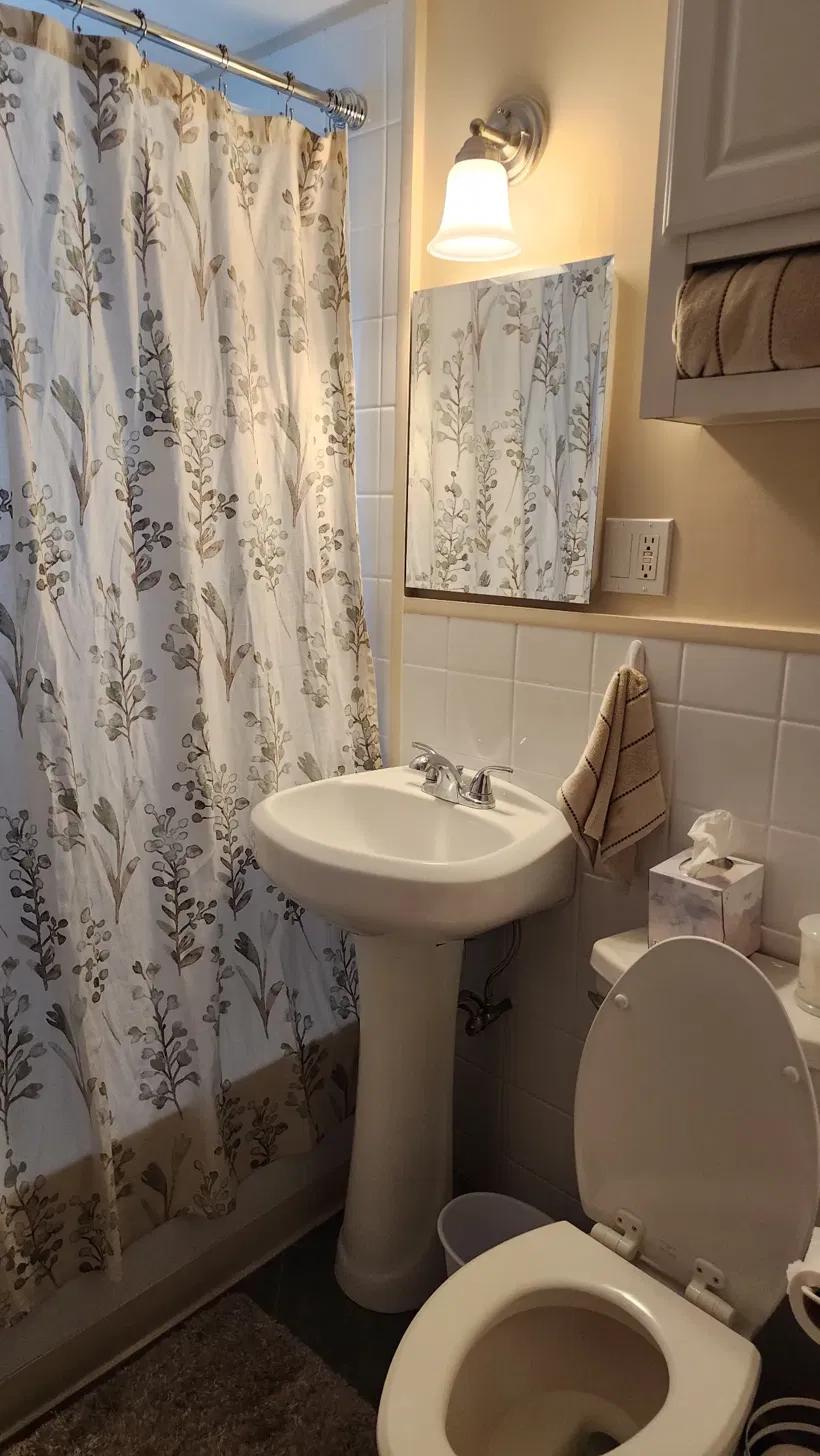The bathroom with a floral shower curtain and pedestal sink