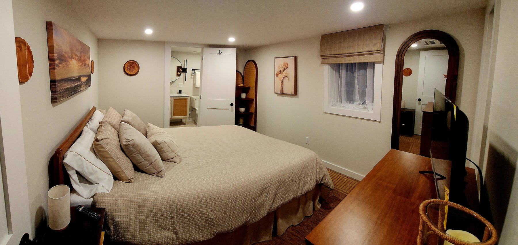 A downstairs bedroom with a large bed, woven accents, and a bathroom beyond the open door