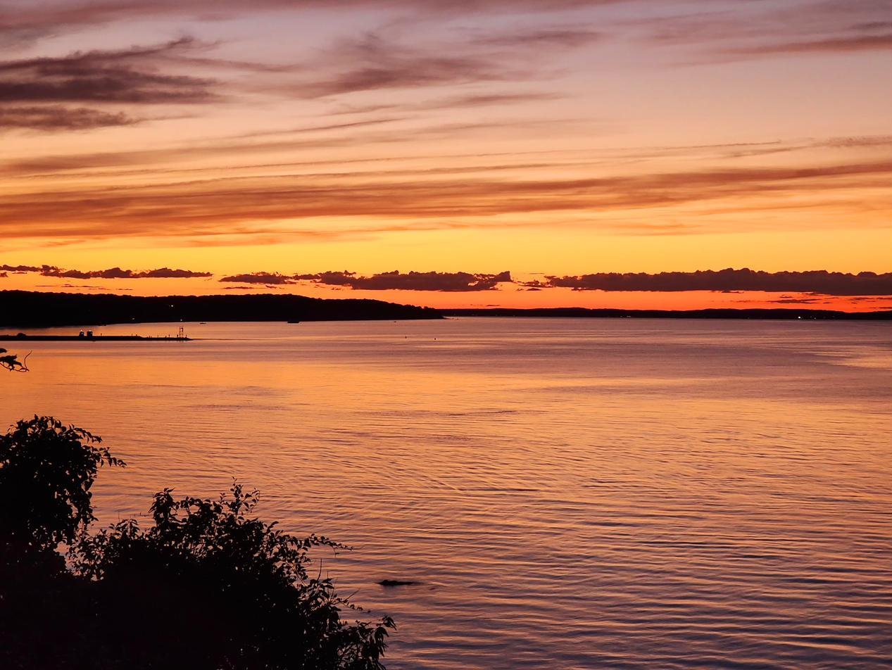 Deep orange, amber, and purple banded sunset sky over Peconic Bay