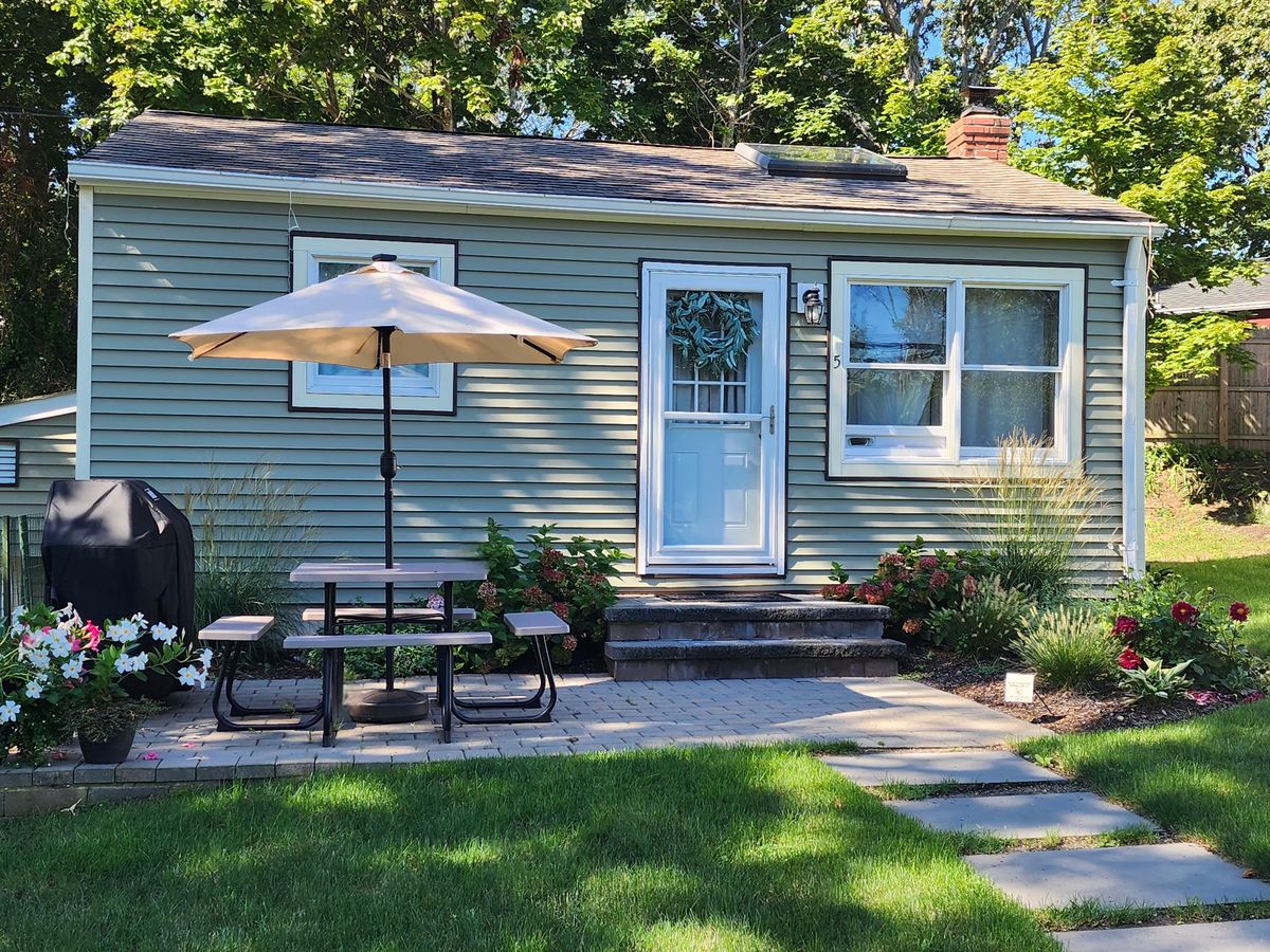 Cottage 5, The Classic exterior, sage green cottage with front door, picnic table, and open umbrella