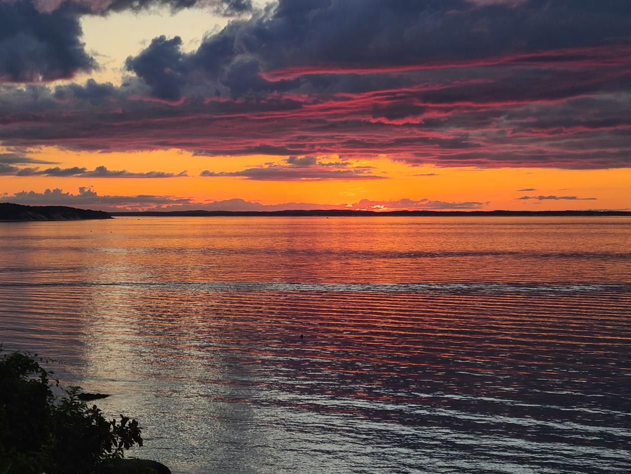 Magenta storm clouds at sunset reflected on the bay