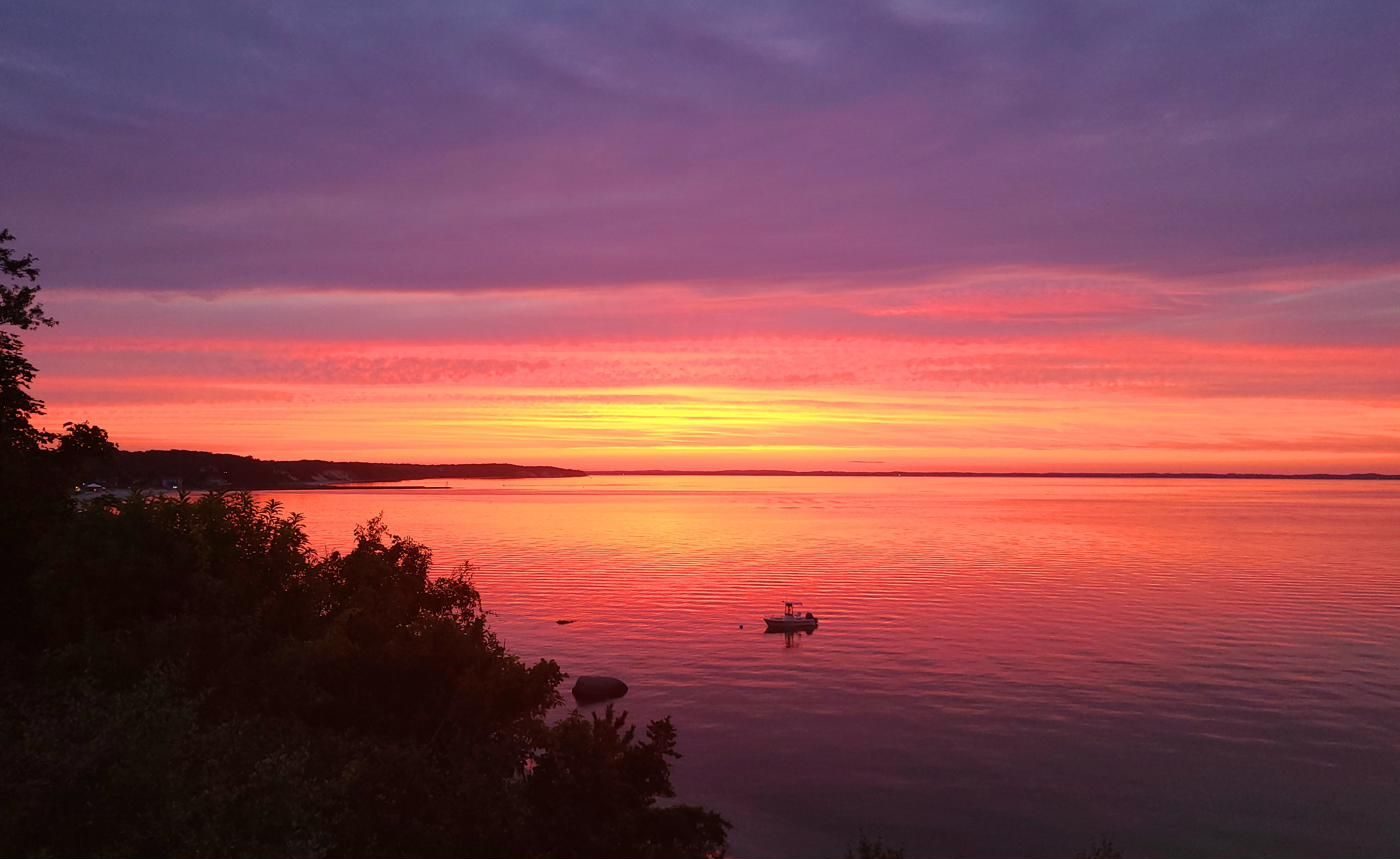 A small boat anchored in a pink and gold sunset