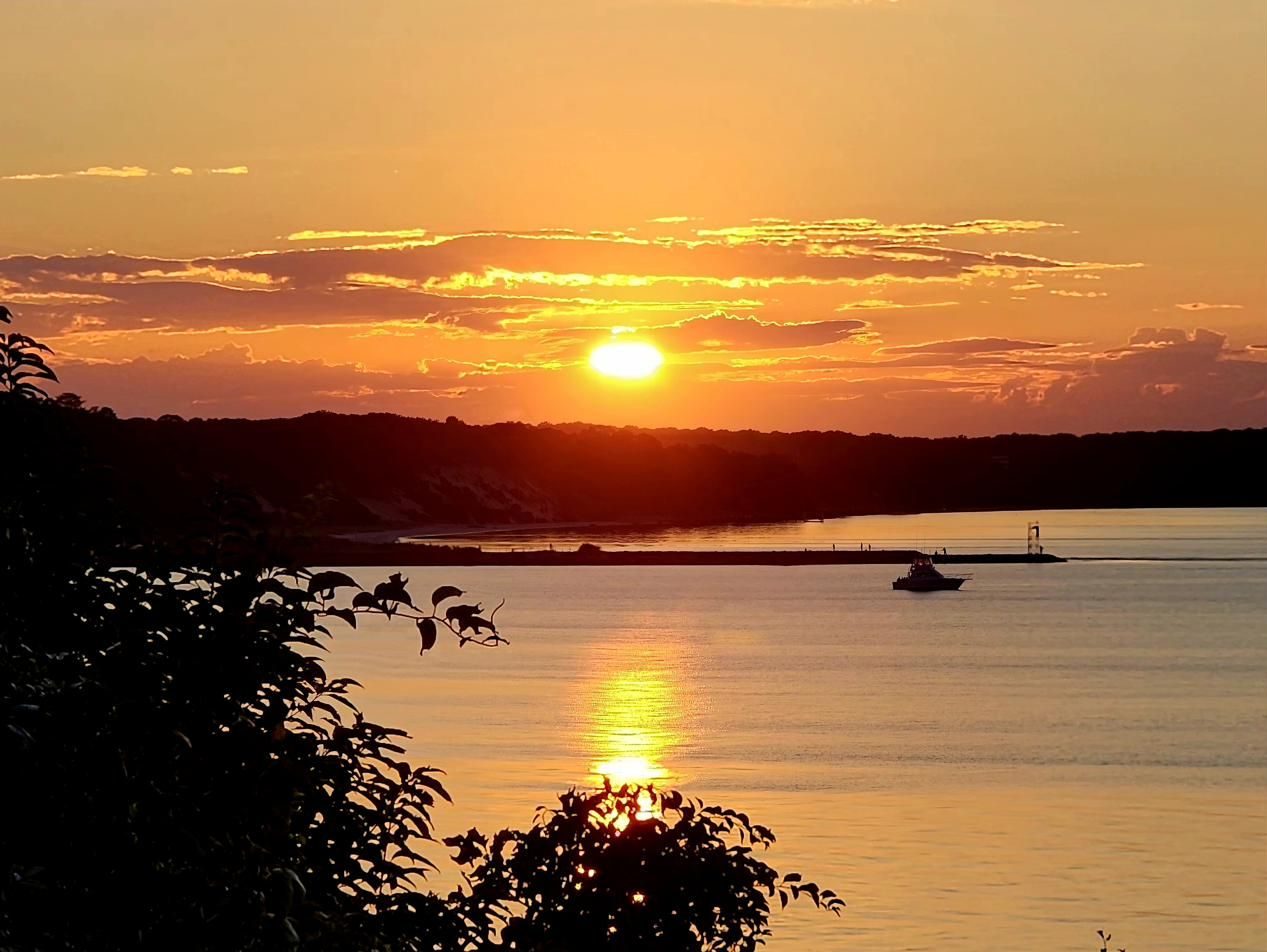 Sunset over the bay with a boat passing the jetty