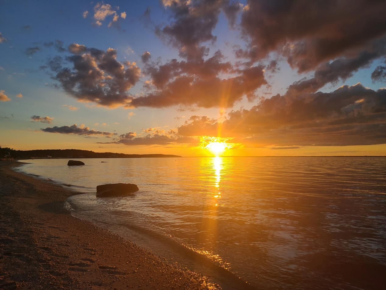 Sunset over the beach with rocks in the shallows