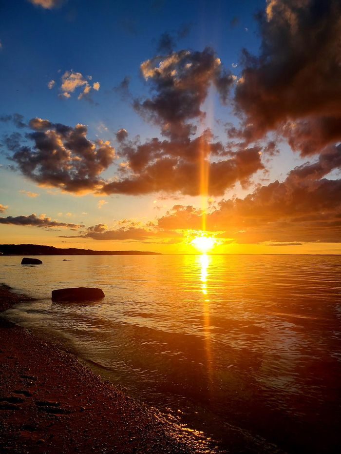 Sun rays breaking through clouds over a rocky shoreline