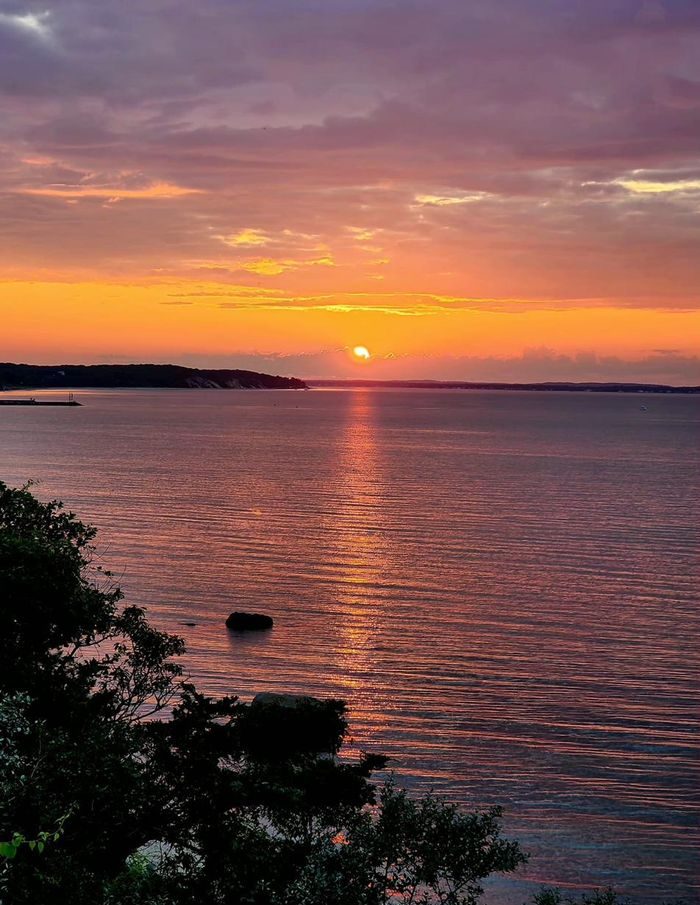 The sun setting into a band of clouds over the bay
