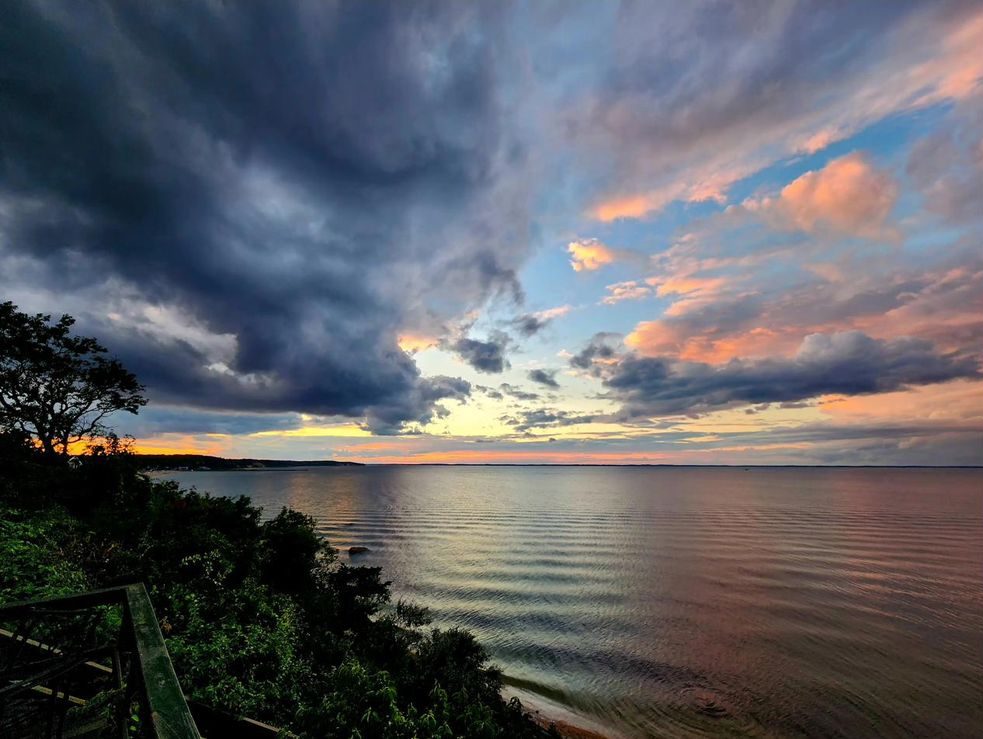 Storm clouds clearing at sunset over the water