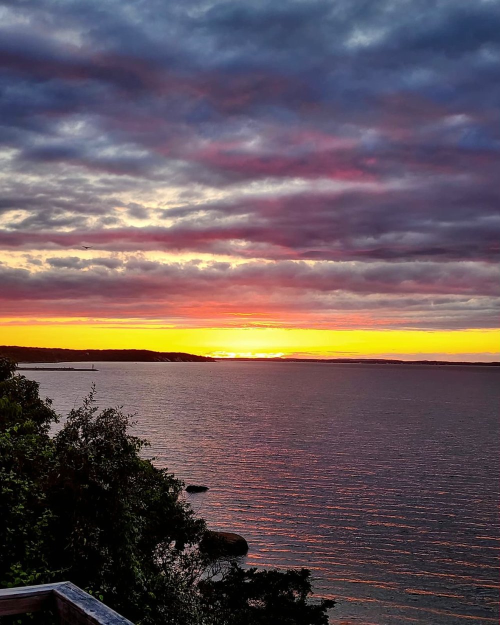 Dramatic magenta storm clouds parting over Peconic Bay at sunset