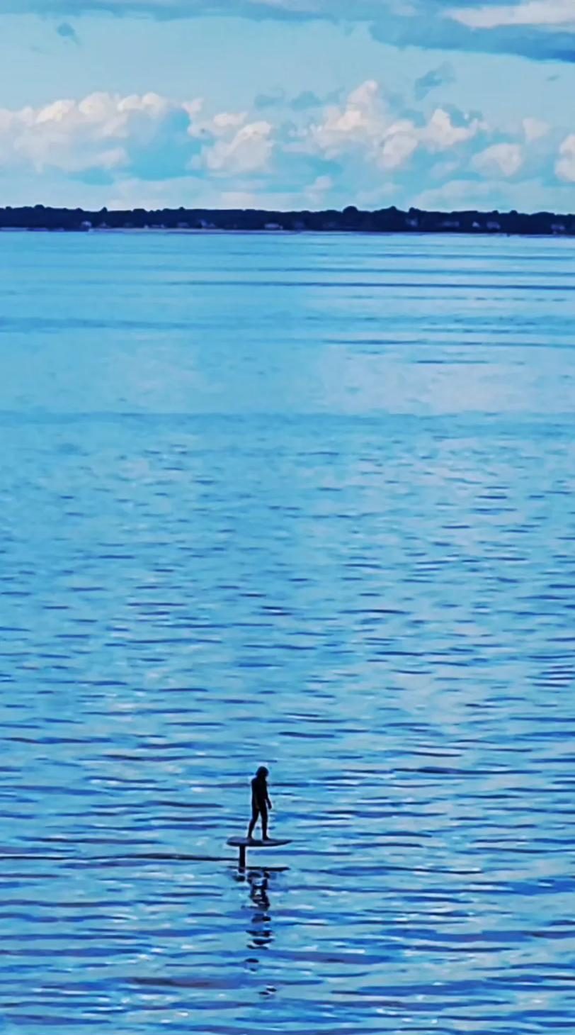 A rider on a hydrofoil board gliding above the calm water